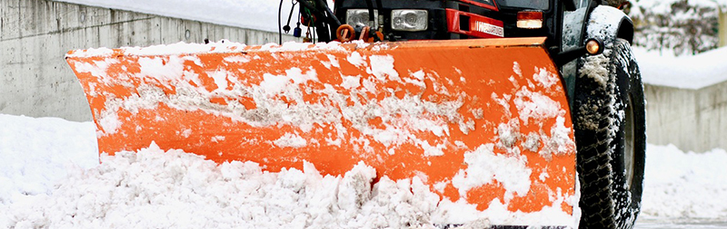Odhrnování sněhu z příjezdové cesty traktorem s čelní sněhovou radlicí.